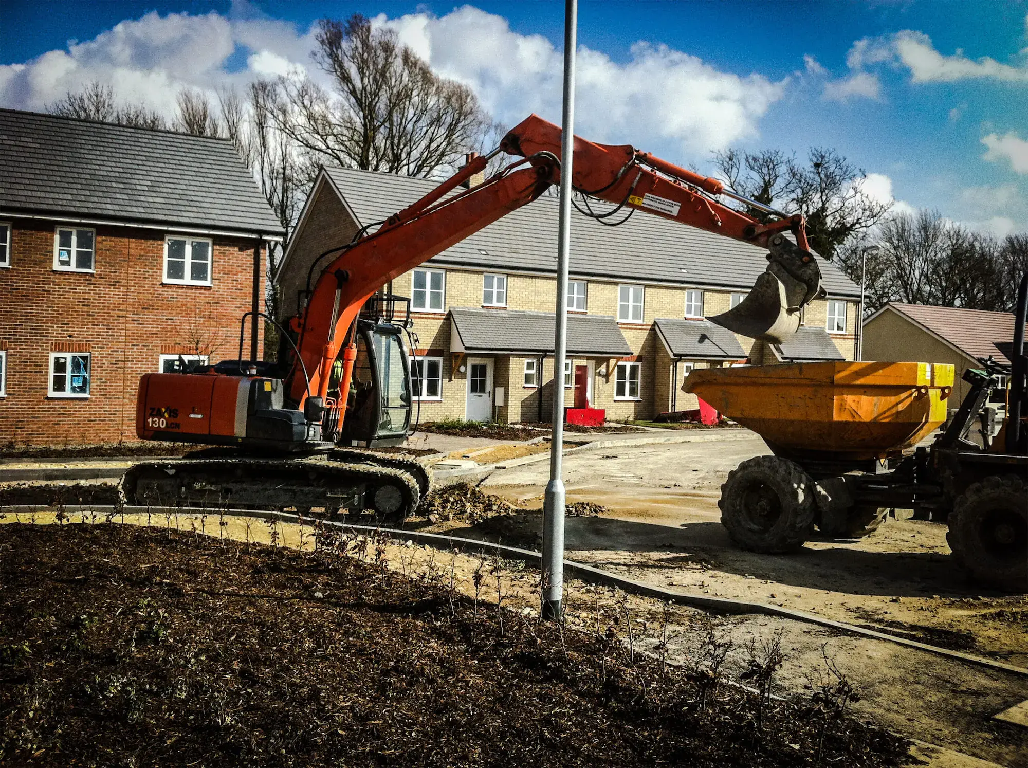 Excavator loading a dumper on a housing site